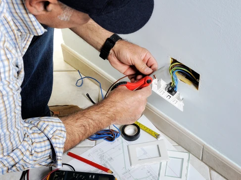 Électricien professionnel installant un interrupteur mural dans un intérieur résidentiel