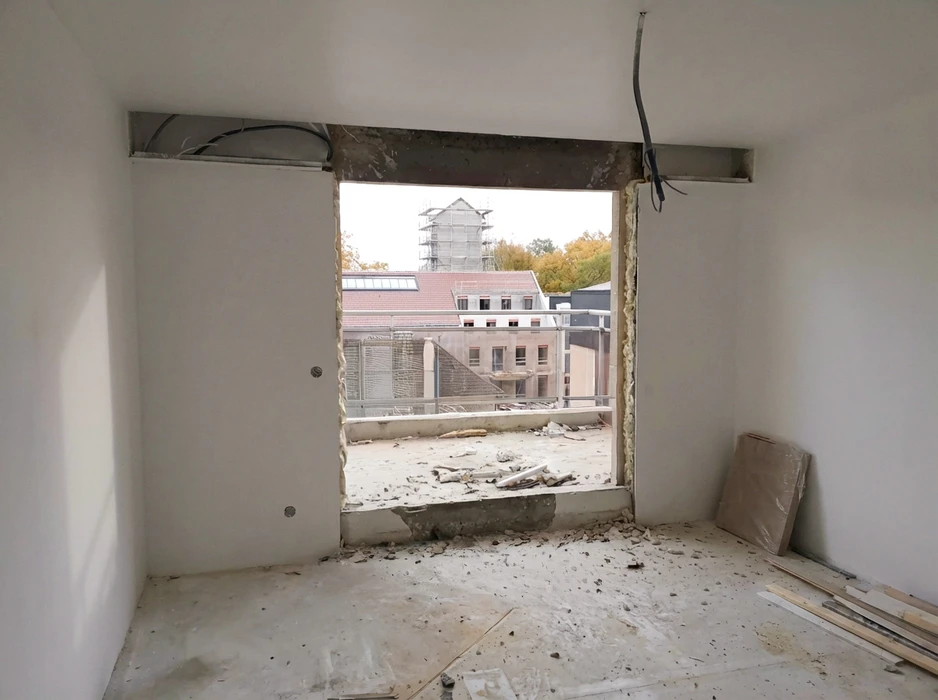 Intérieur d'un chantier de rénovation en cours, vue depuis une pièce vers l'extérieur