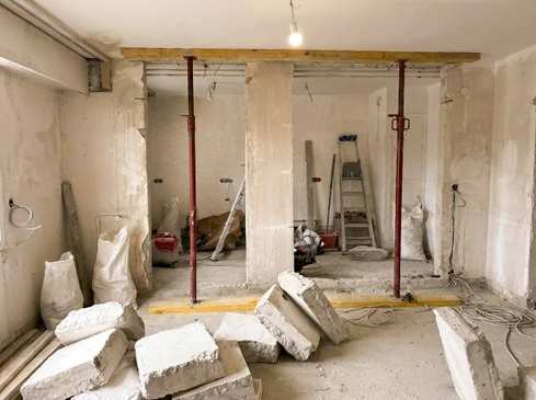 Chantier de r&eacute;novation int&eacute;rieur avec mur en briques apparentes et poutre m&eacute;tallique endommag&eacute;e