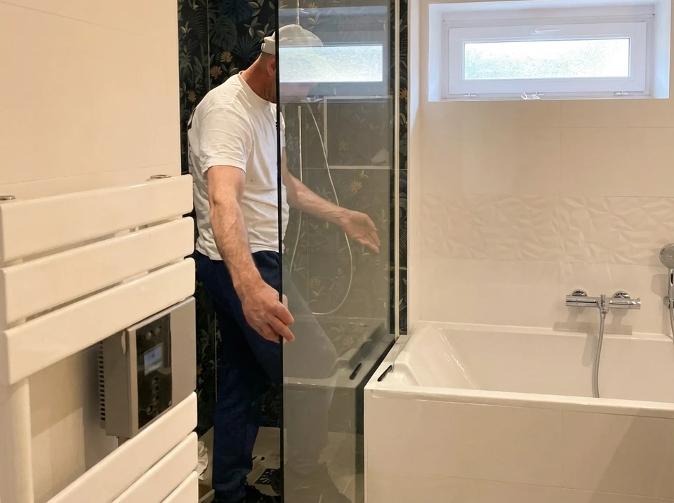 Artisan carreleur agenouillé sur un chantier intérieur appliquant du mortier-colle sur carrelage avec une truelle