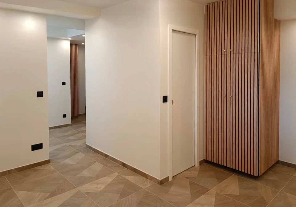 Une personne peint un mur intérieur blanc avec un rouleau à peinture