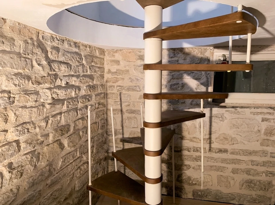 Un artisan en combinaison blanche à bandes rouges applique un enduit sur un mur intérieur en rénovation